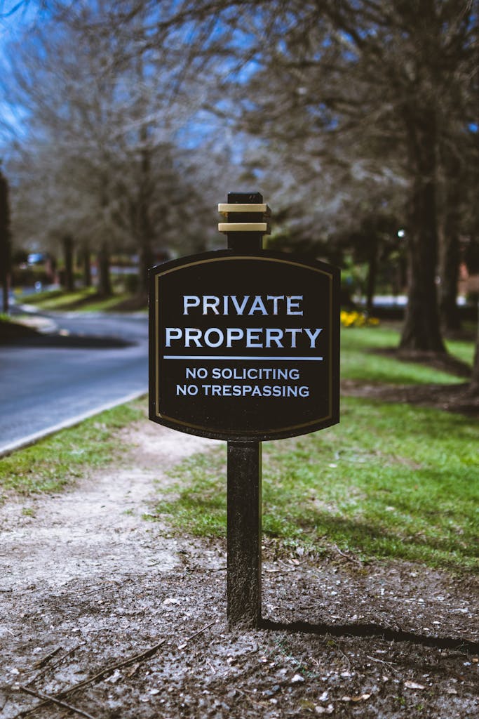 Black sign displaying 'Private Property' warning with trees in the background.